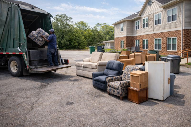 Senior living facility maintenance team removing heavy furniture near dumpsters