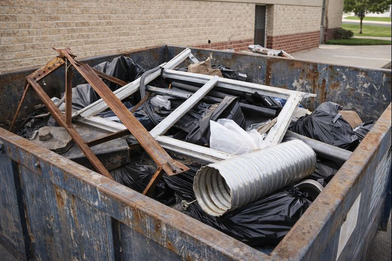 Metal items improperly placed inside a trash dumpster at a commercial property realistic photo